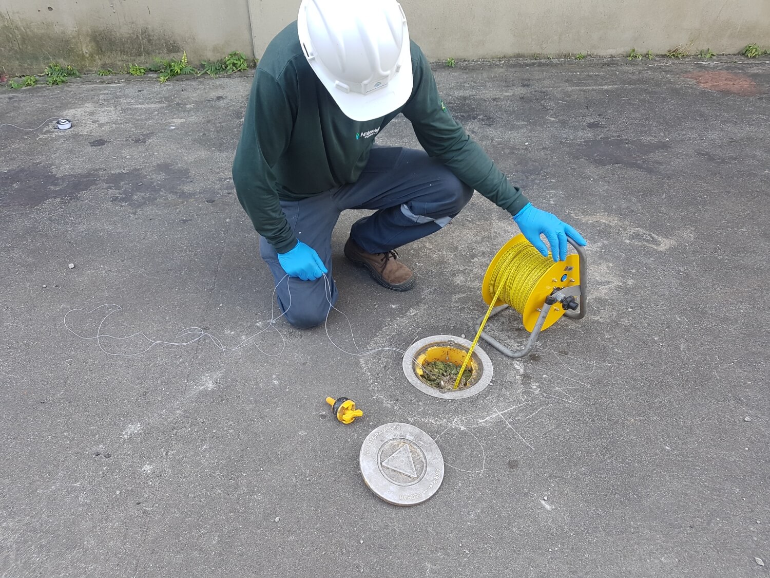 Profissional da Ambsolution Engenharia Ambiental usa medidor de nível em poço de água para monitoramento ambiental em campo